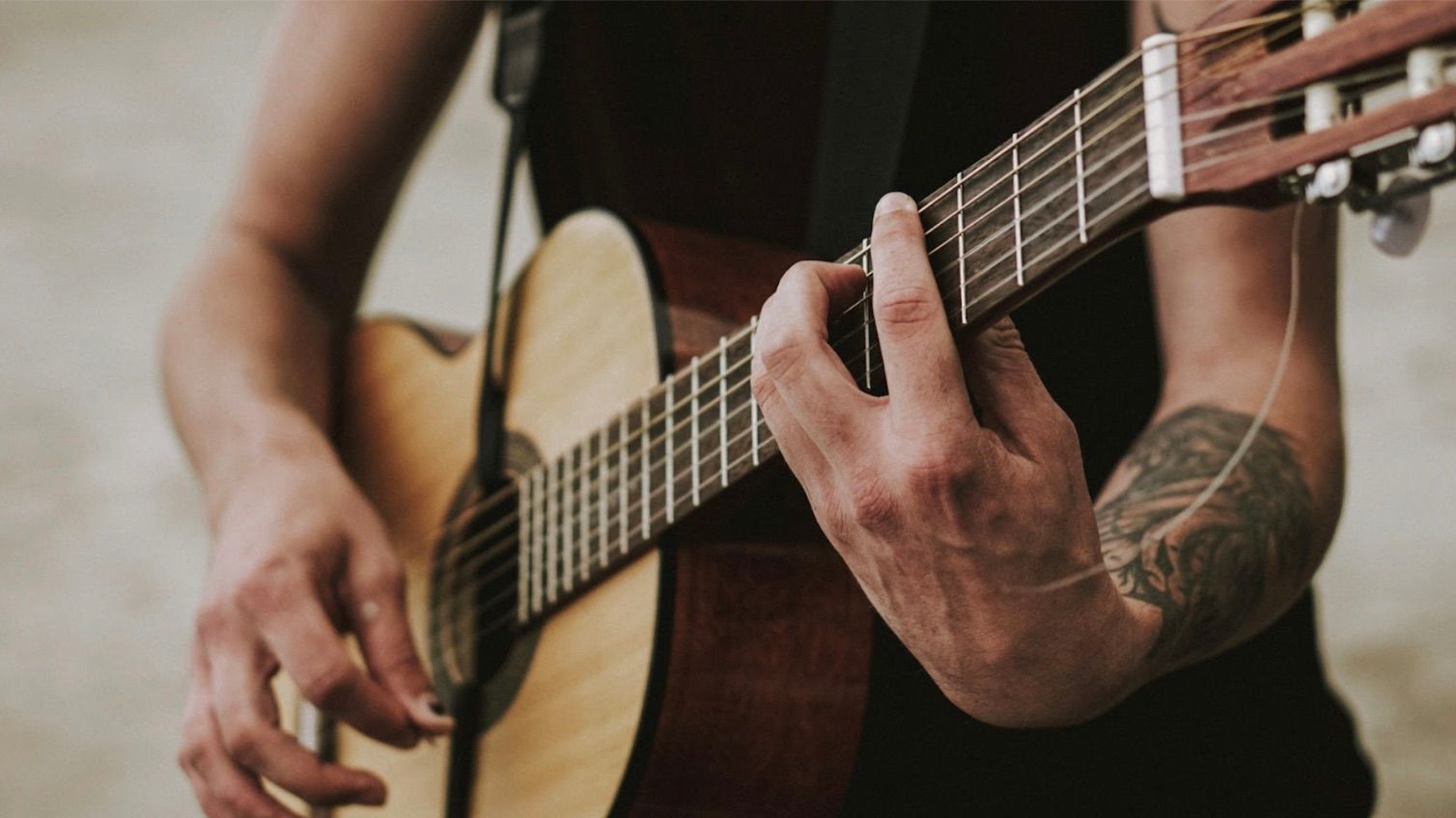 Close-up of hands playing chords on an acoustic guitar during a lesson