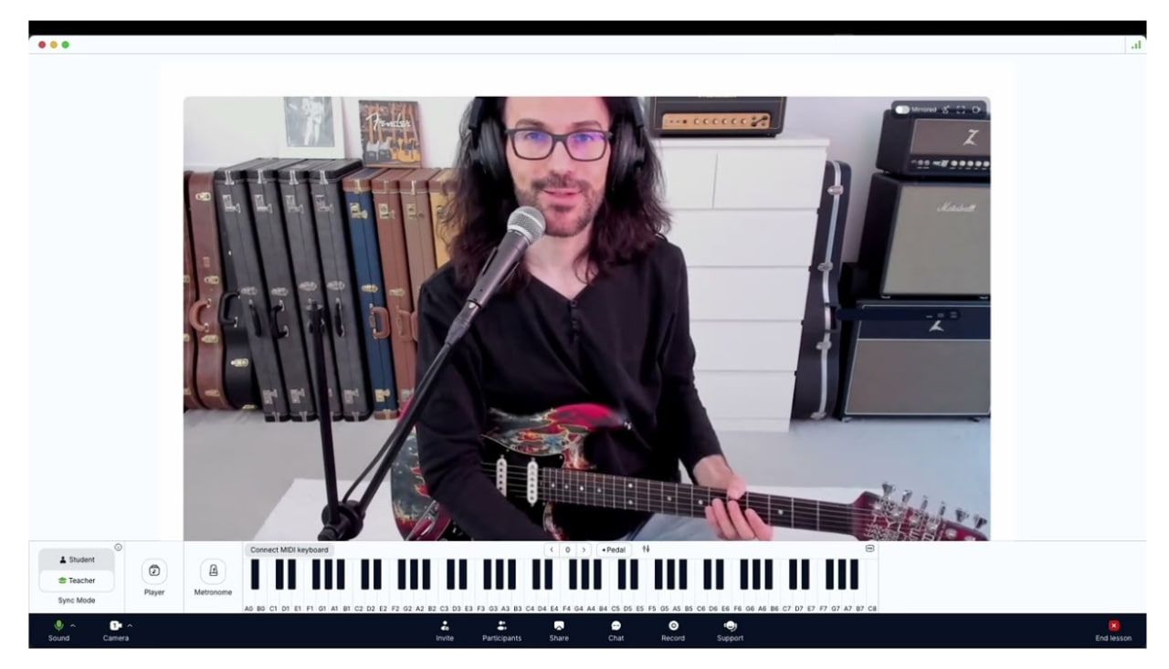 Musician using MOOZ platform with guitar, headphones, and on-screen piano keys
